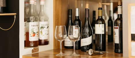 A wine rack with various bottles and two empty wine glasses on a wooden counter.