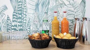 Een tafel met glazen, twee manden croissants en flessen jus d'orange en sinaasappelsaus.