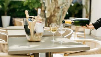 Une bouteille de champagne est versée dans un verre sur une table, à côté d’une autre bouteille de champagne et d’un seau rempli de glaçons.