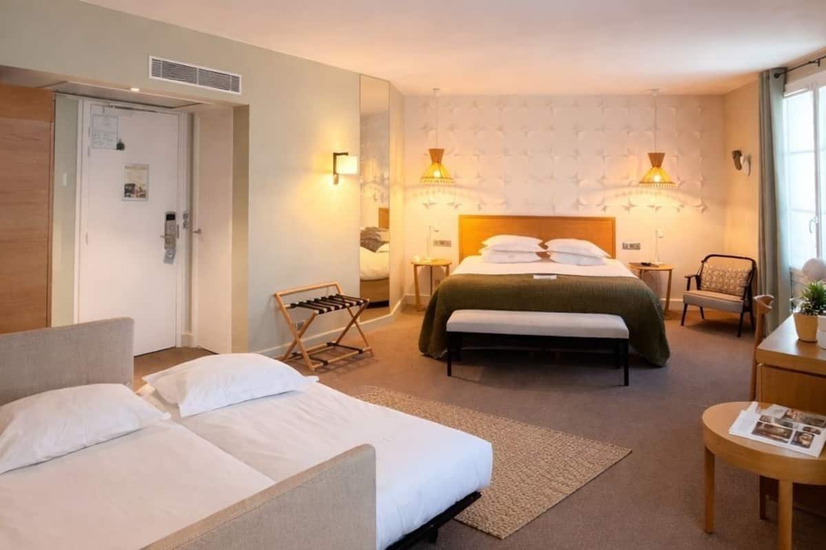 Hotellihuone, jossa on sänky, sohva, työpöytä ja tuoli.