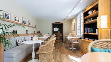 Un interior acogedor con un sofá, sillones de mimbre, una estantería y un comedor.