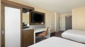 A hotel room with a bed, a desk with a chair, a television, and a wardrobe. - The Lodge at Duke Medical Center (Durham)