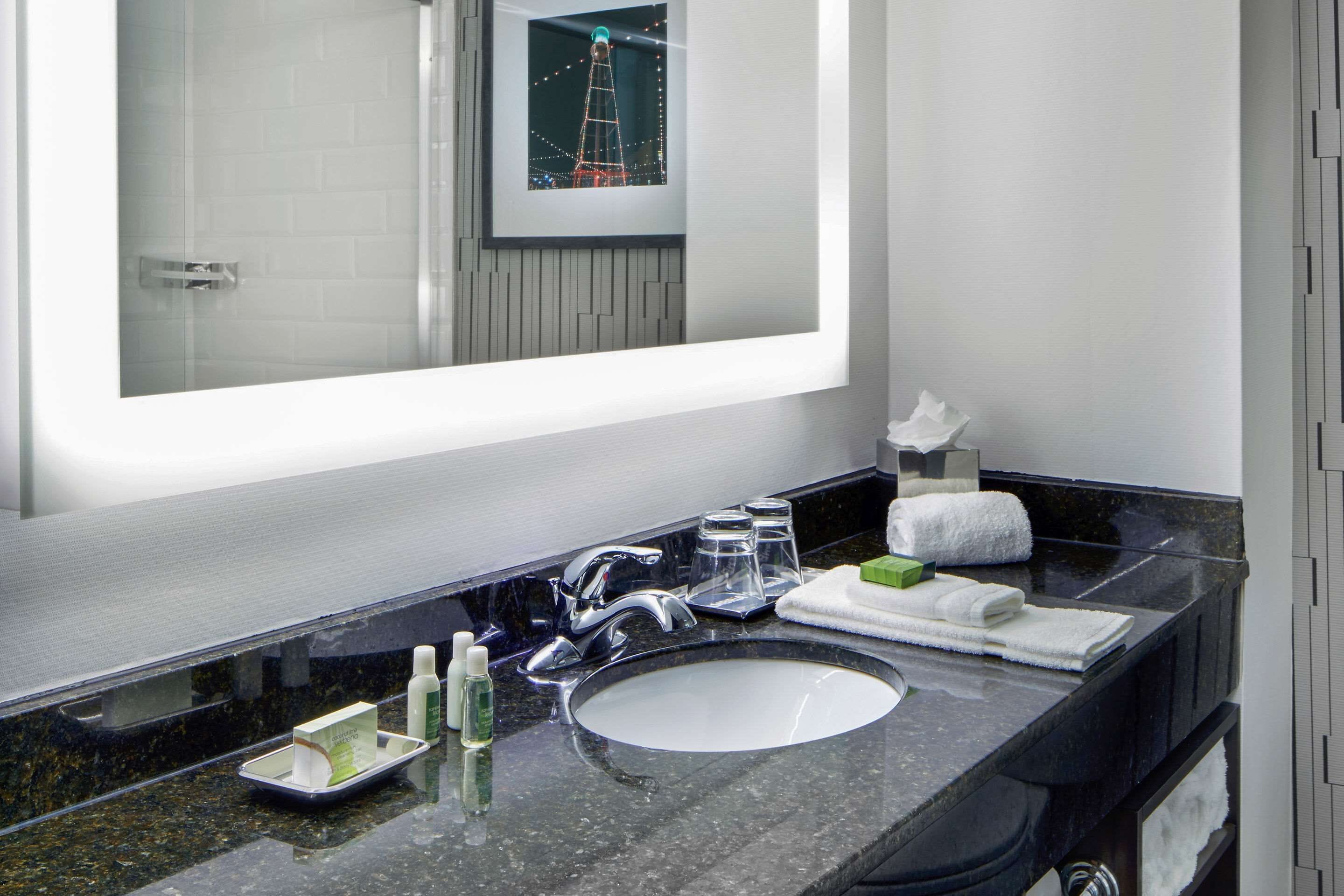 Un baño moderno con un espejo grande, un lavabo y una zona de tocador.