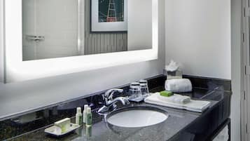 A modern bathroom with a large mirror, a sink, and a vanity area.