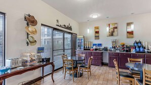 Un comedor con sillas de madera y una mesa, una cocina con armarios morados y un refrigerador.