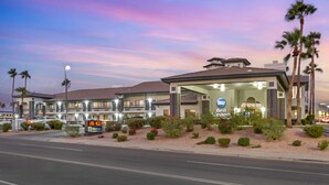 Un hotel Best Western con un amplio estacionamiento, palmeras y un cielo al atardecer.