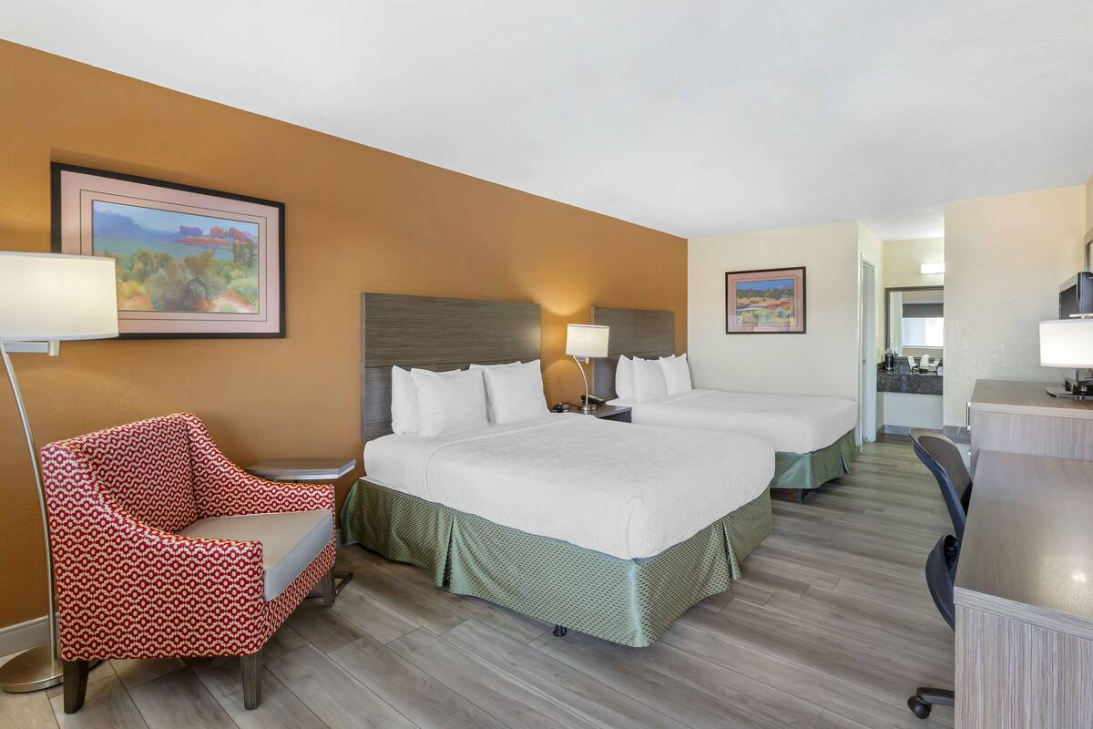 A hotel room with a large bed, two bedside tables, a chair, and a desk.