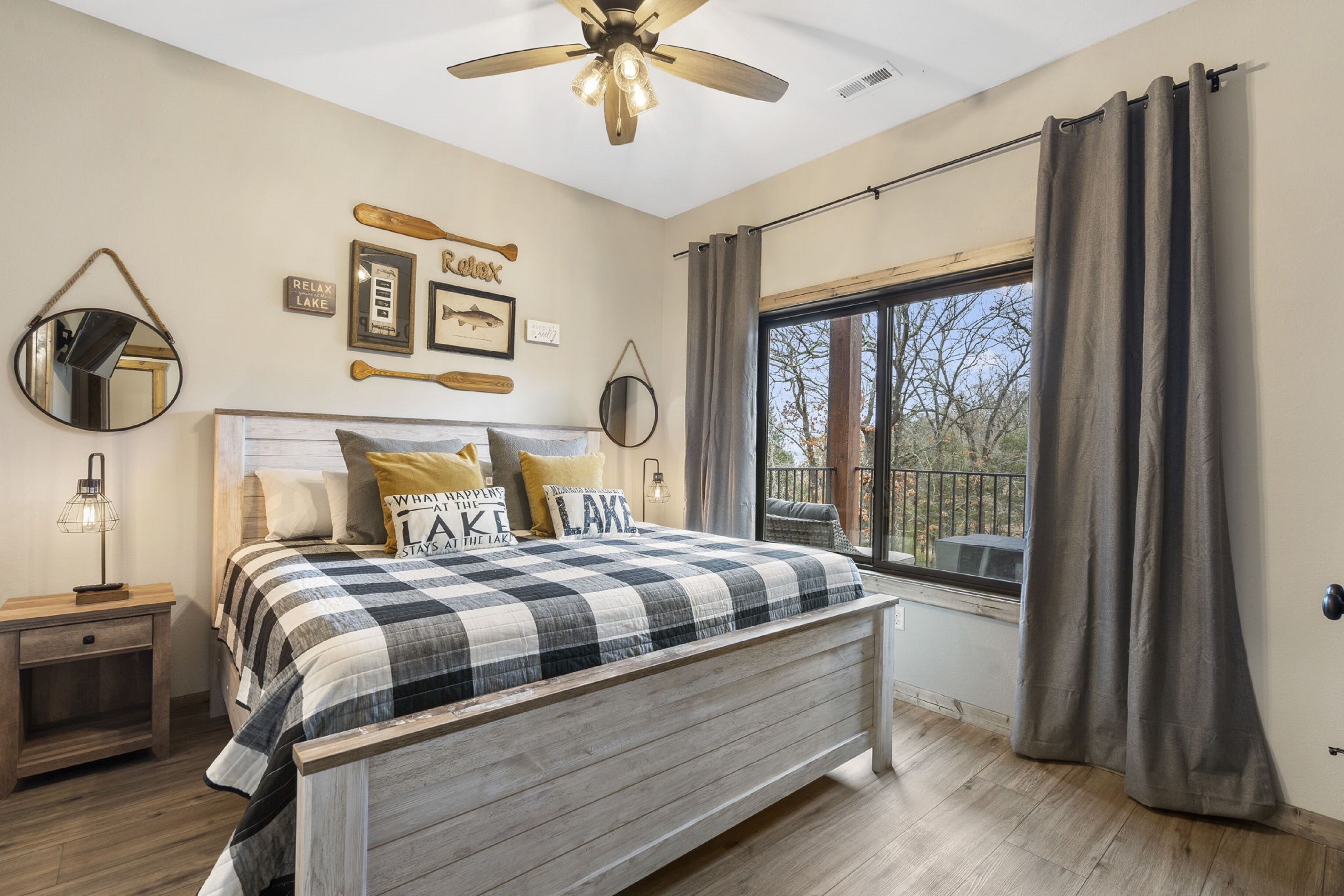 A bedroom with a bed, a nightstand, a ceiling fan, and a window with curtains.