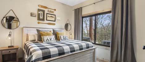 A bedroom with a bed, a nightstand, a ceiling fan, and a window with curtains.