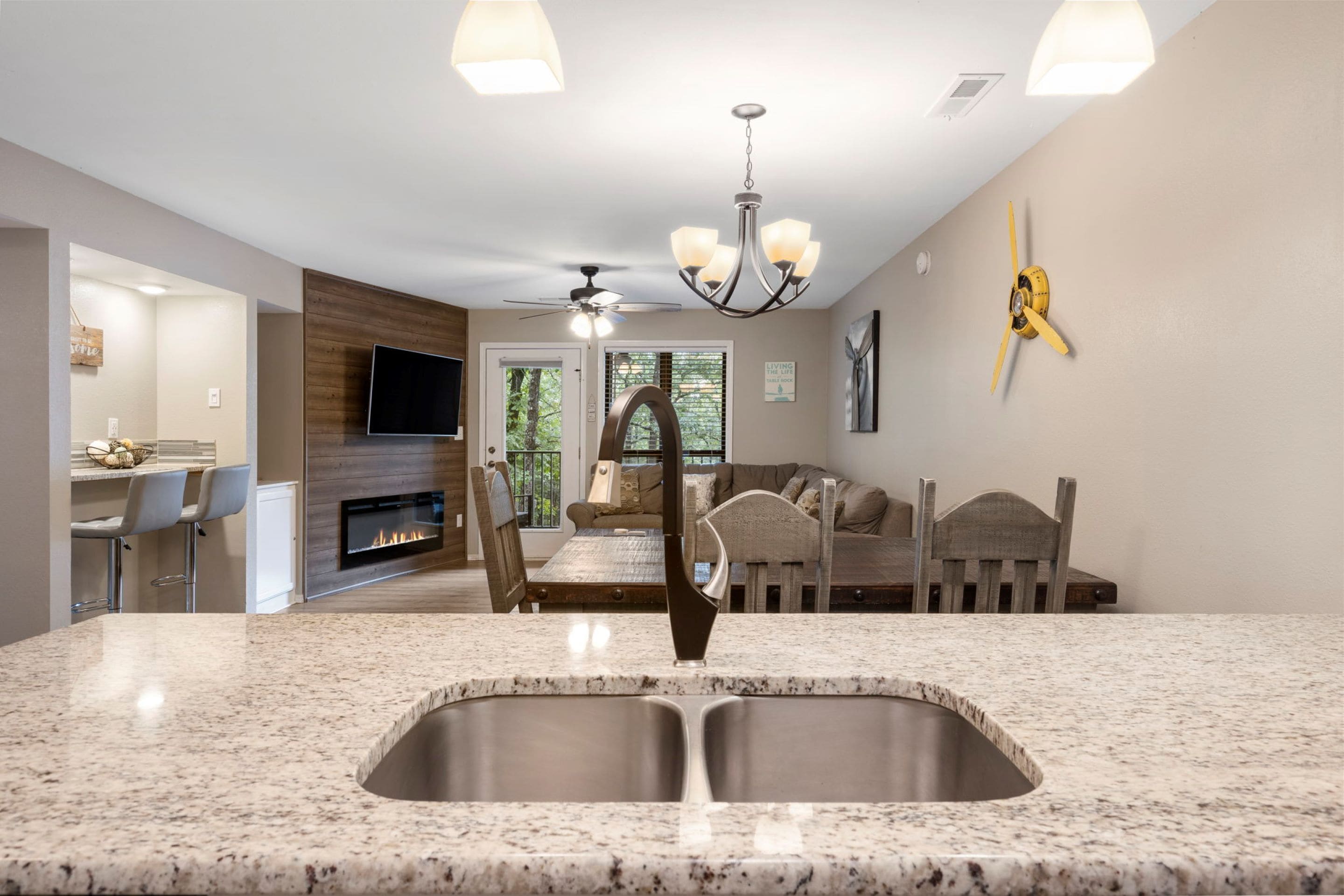 A modern kitchen with a granite countertop, stainless steel sink, and a built-in fireplace.