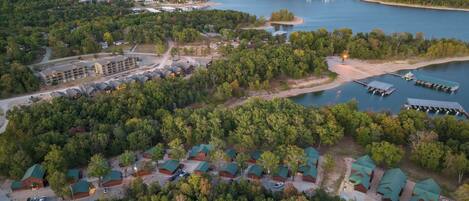 An aerial view of a lakeside resort with multiple cabins, a large building complex, and docked boats.