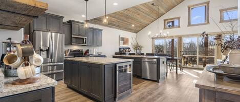A spacious kitchen with dark cabinetry, stainless steel appliances, and a large island.