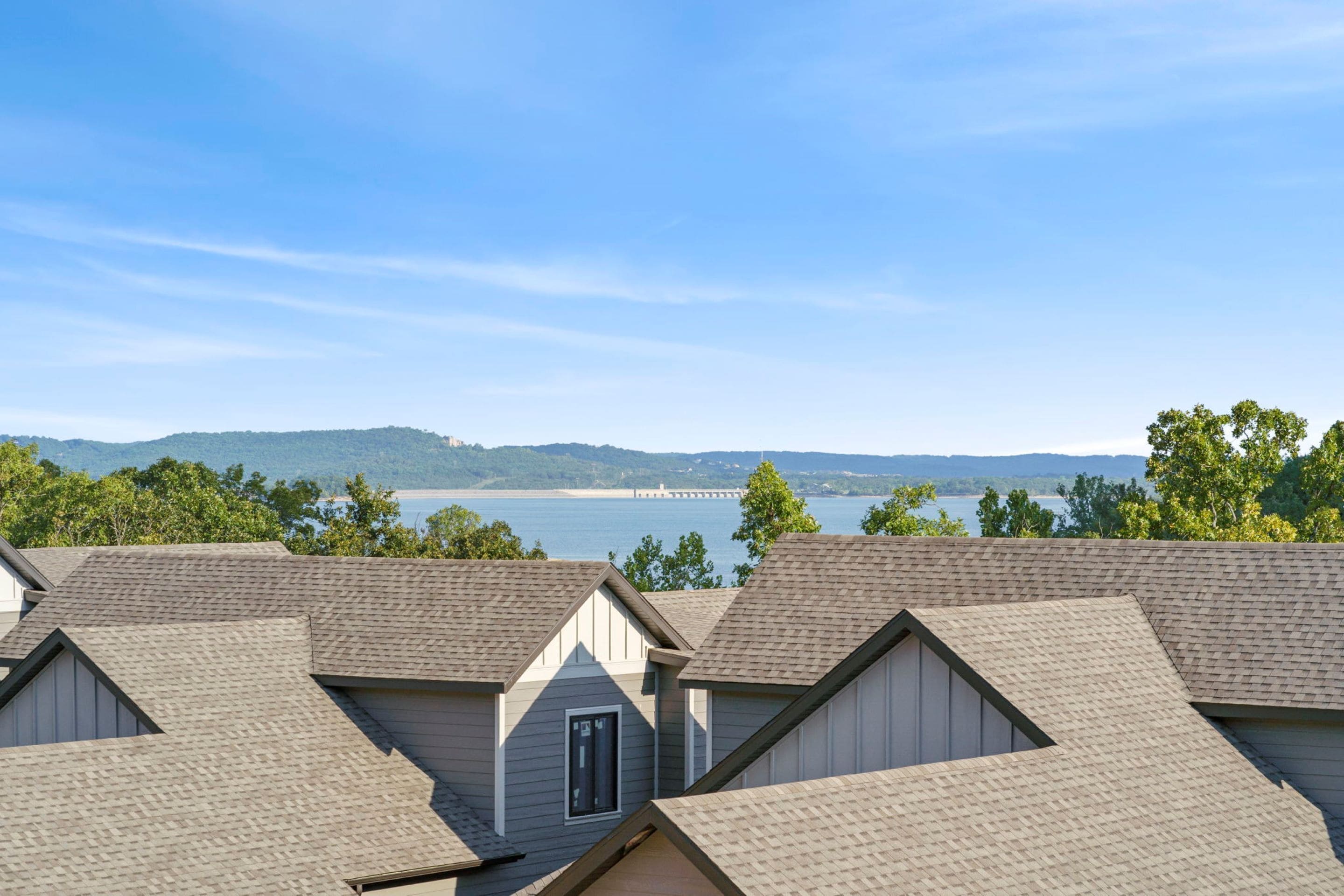 A row of houses with sloped roofs and a view of a lake and distant hills.