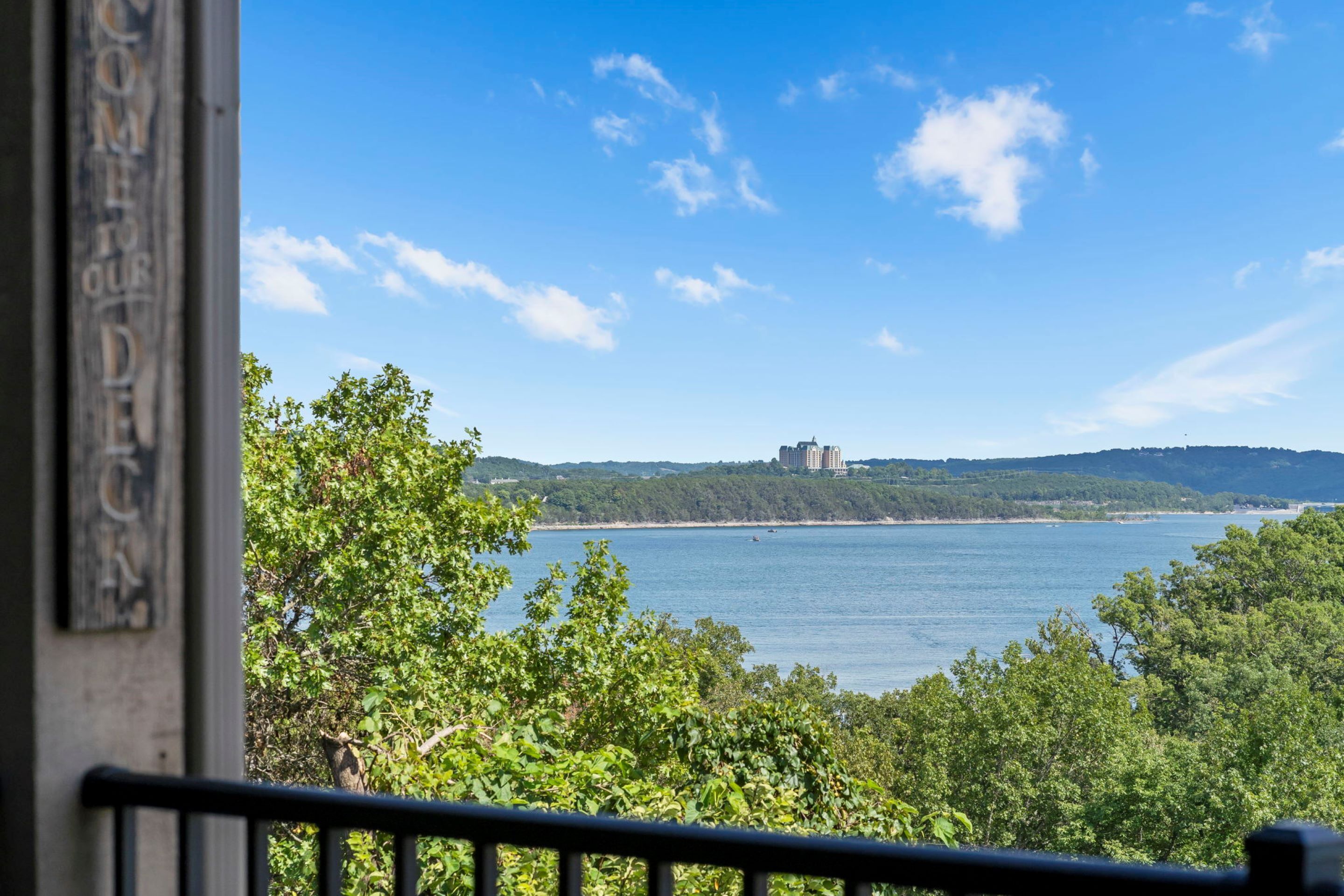 A view of a body of water with a distant building on a hill, surrounded by greenery.