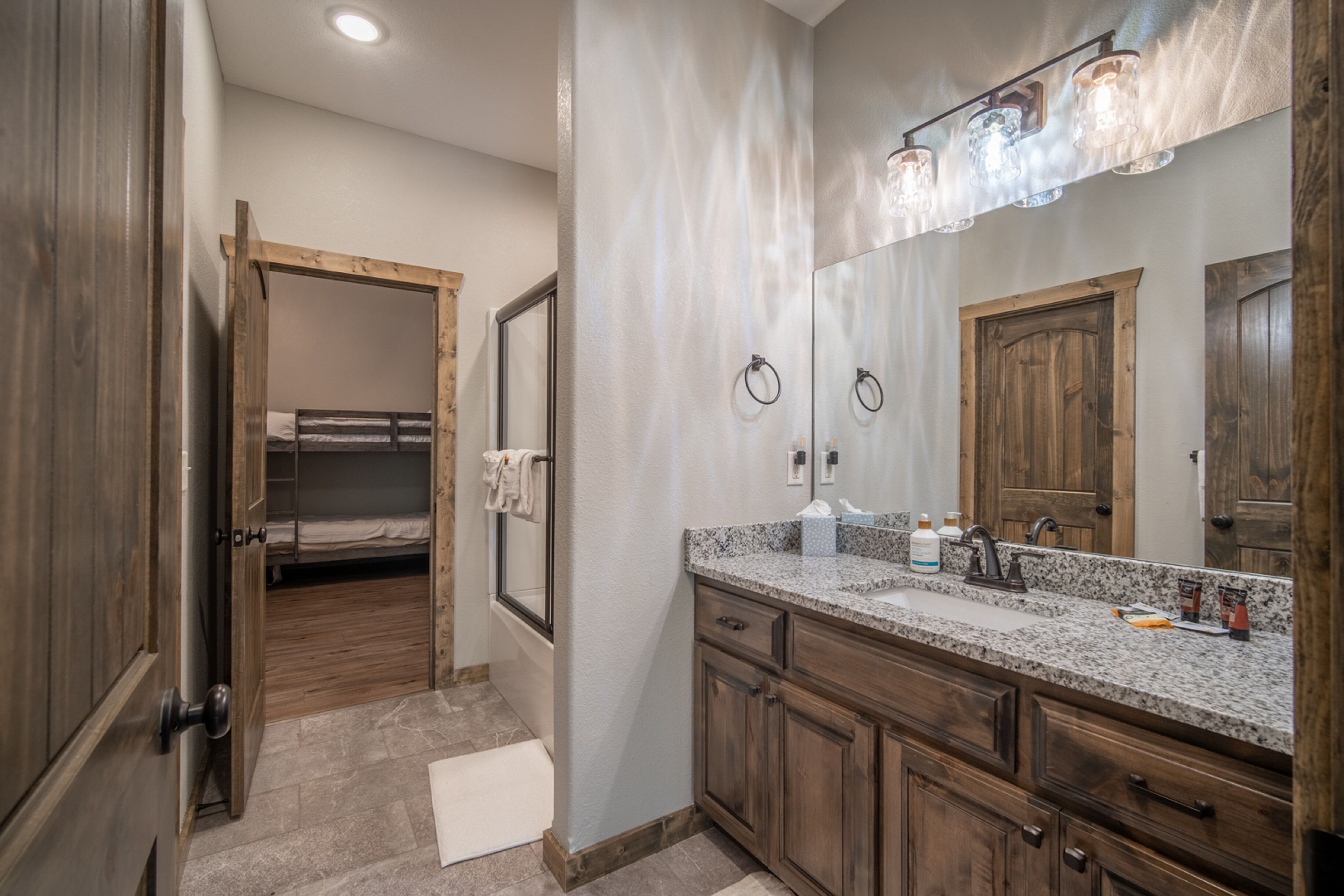A bathroom with a wooden vanity, a large mirror, and a shower area.