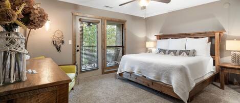 A bedroom with a bed, wooden headboard, bedside tables, a ceiling fan, and a door with glass panels.