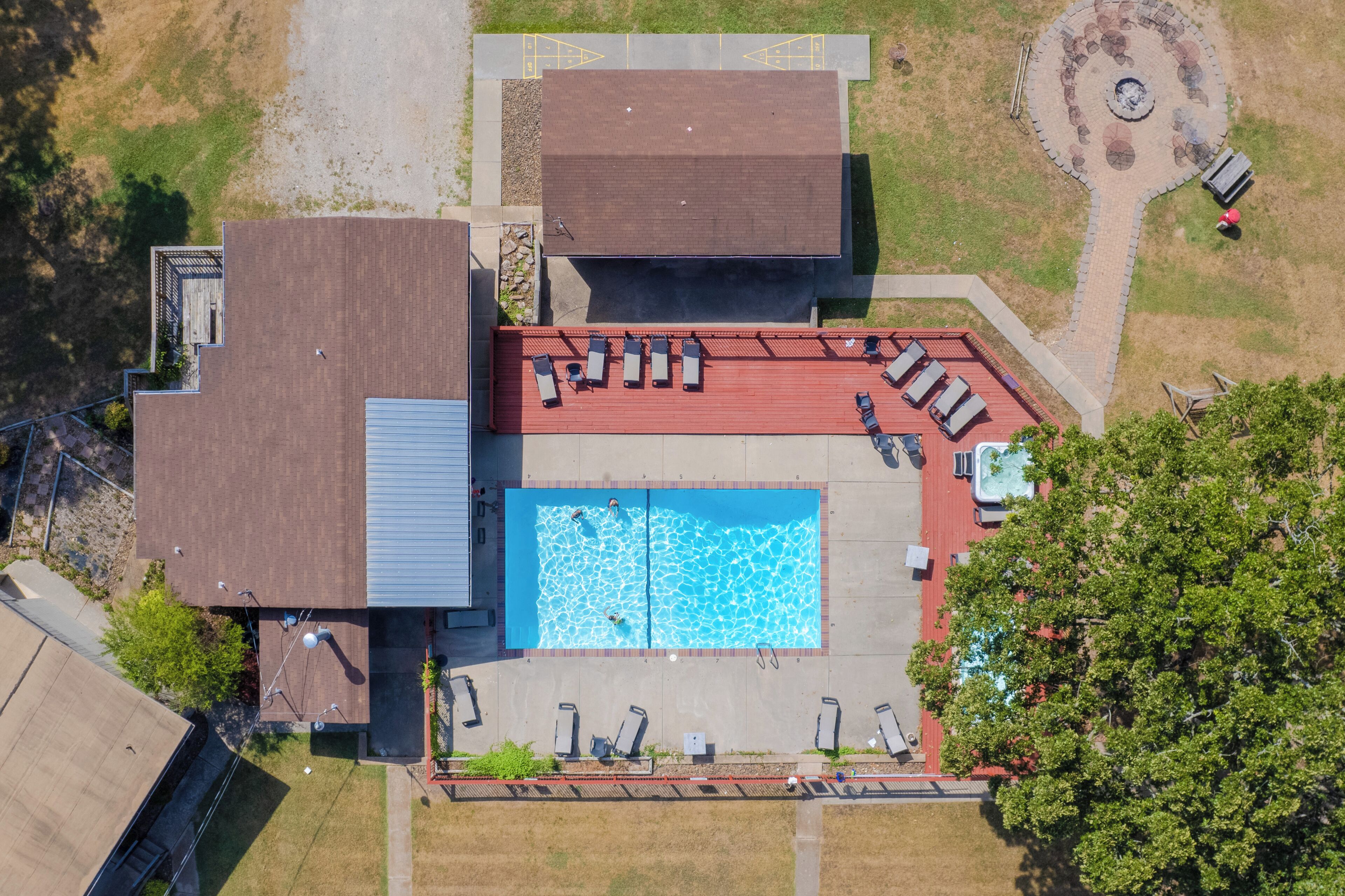 An aerial view of a property with a swimming pool, lounge chairs, and a landscaped garden.