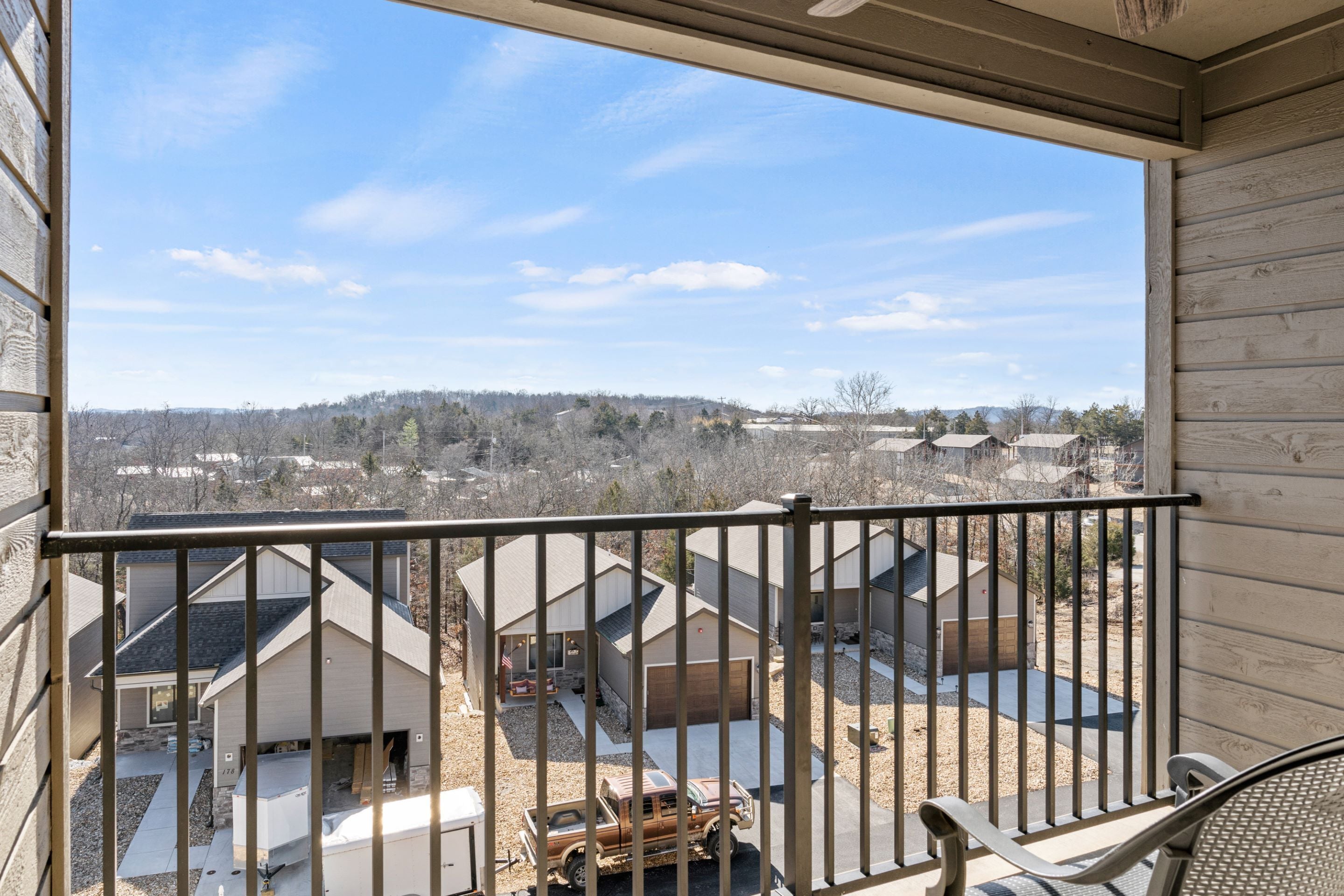 A balcony with a view of a residential area, including houses and a truck.