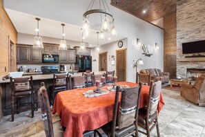 A spacious dining area with a large table, wooden chairs, and a chandelier. - Table Rock Resorts at Indian Point (Branson)