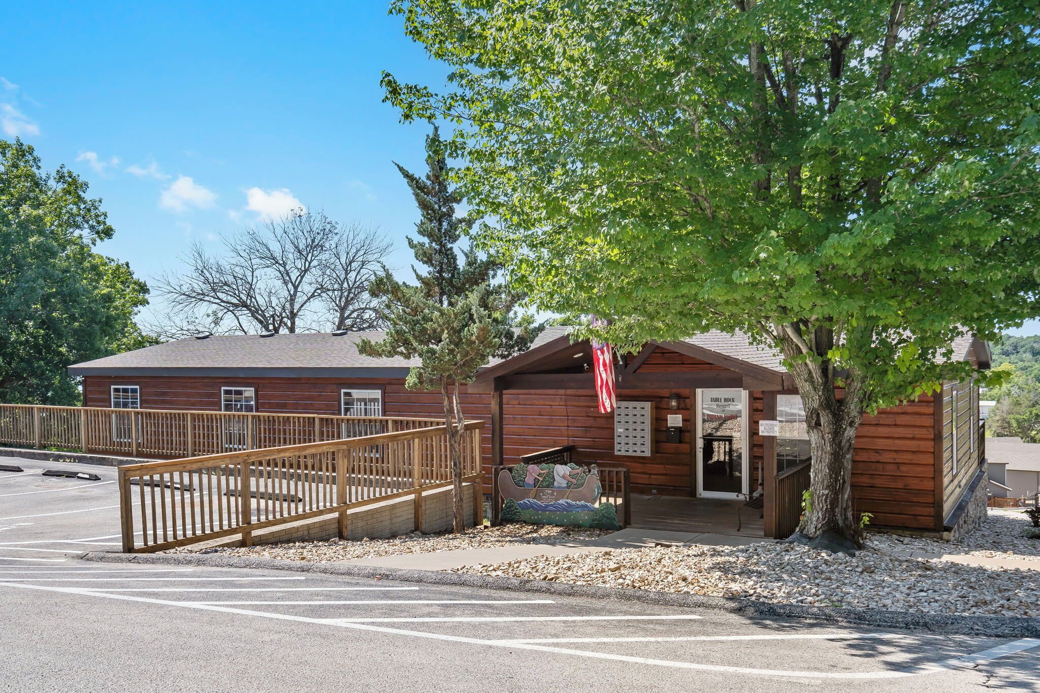 A rustic wooden building with a covered entrance, a wooden fence, and a bench.
