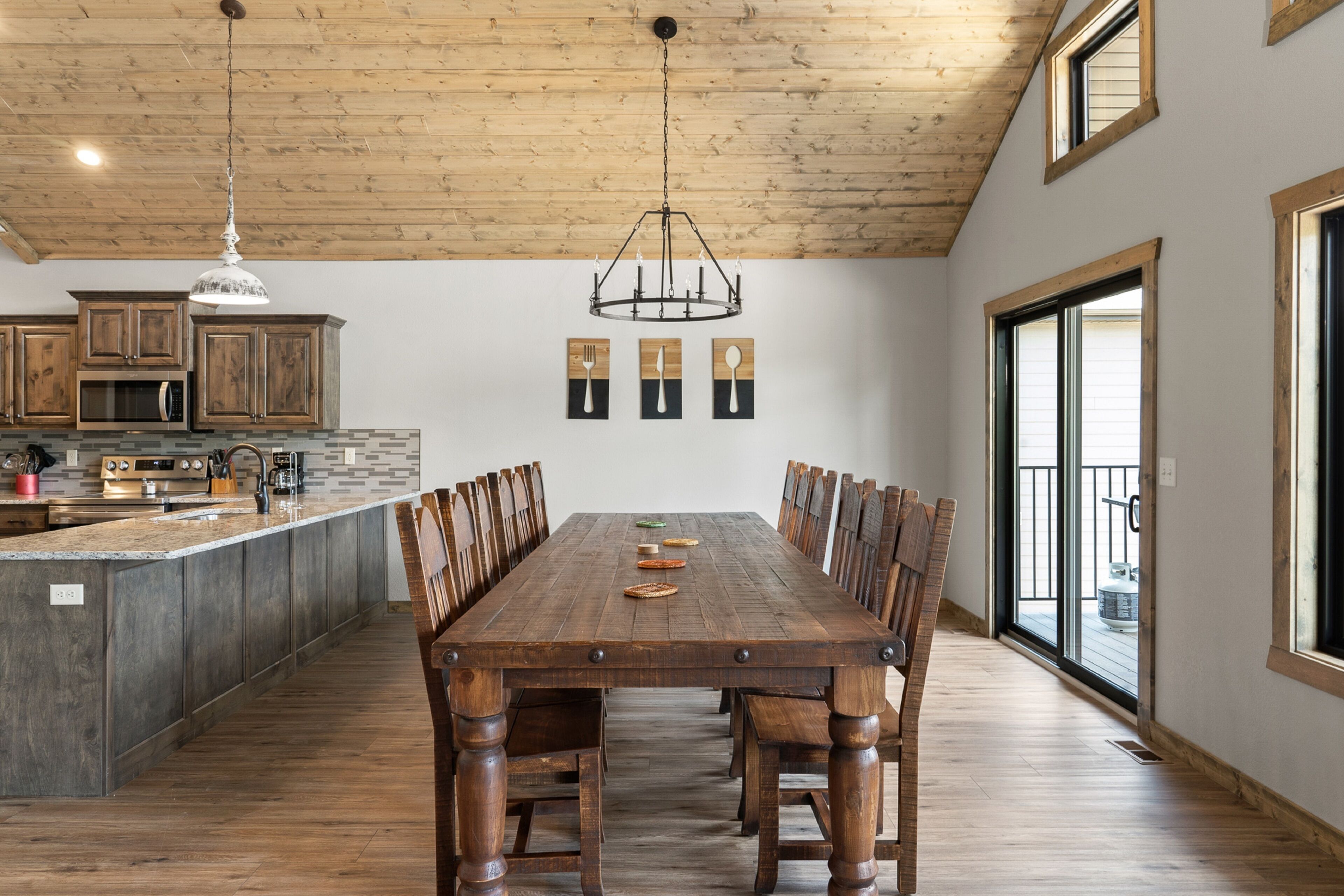 A spacious dining area with a wooden table and chairs, a kitchen with wooden cabinets, and a large window providing natural light.