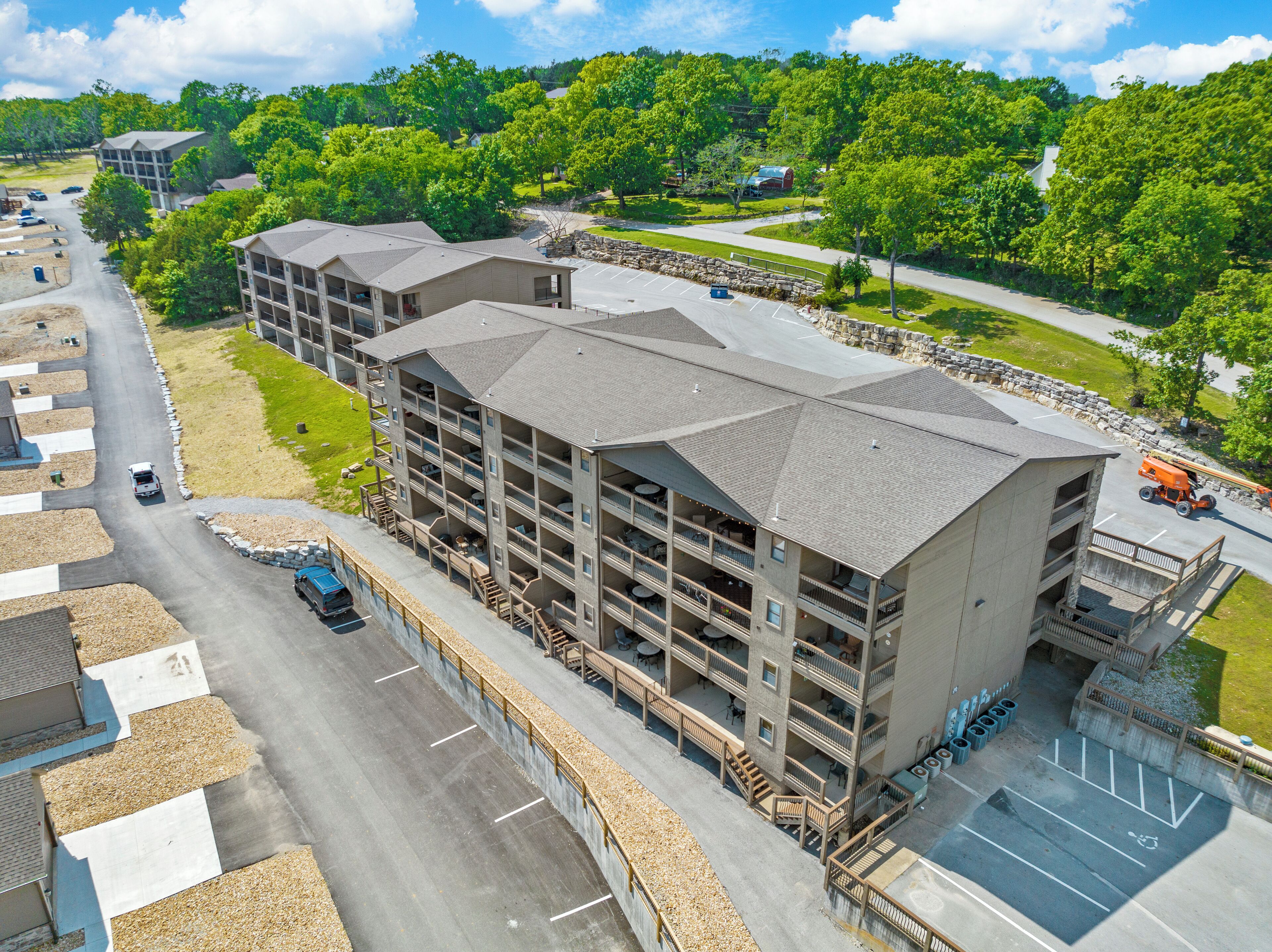 A multi-story hotel with a central courtyard, outdoor seating, and a parking area.