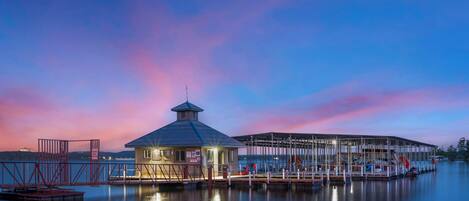 A waterfront dock with a small building, possibly a boathouse, and a covered area with boats.