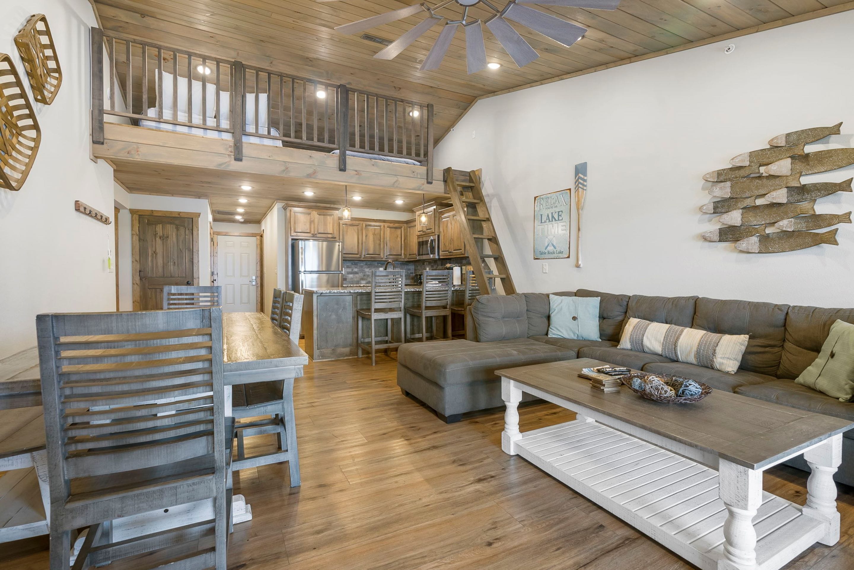 A spacious living area with a wooden ceiling, a staircase, a kitchen, and a dining area.