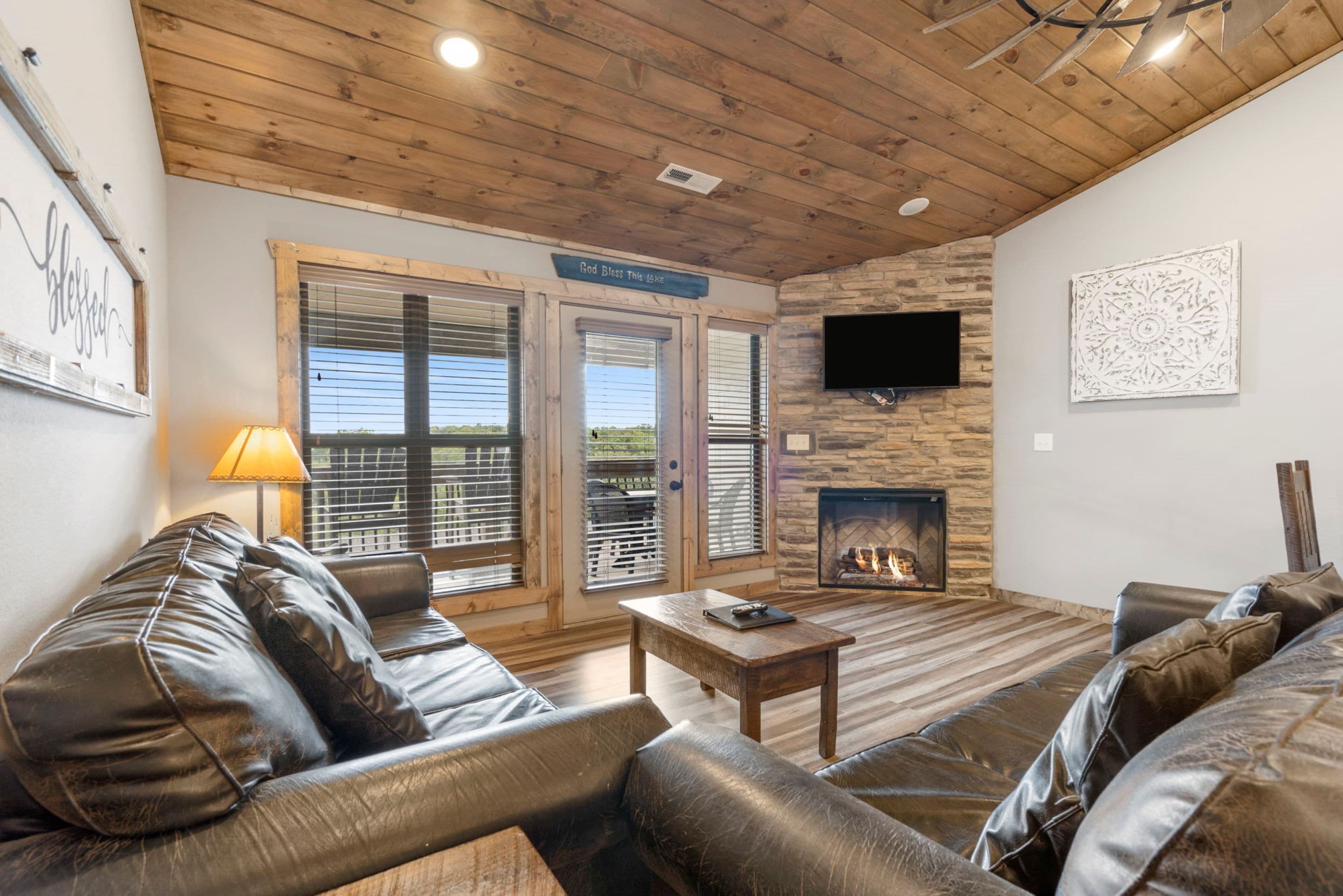 A cozy living room with leather sofas, a fireplace, and a television mounted on the wall.