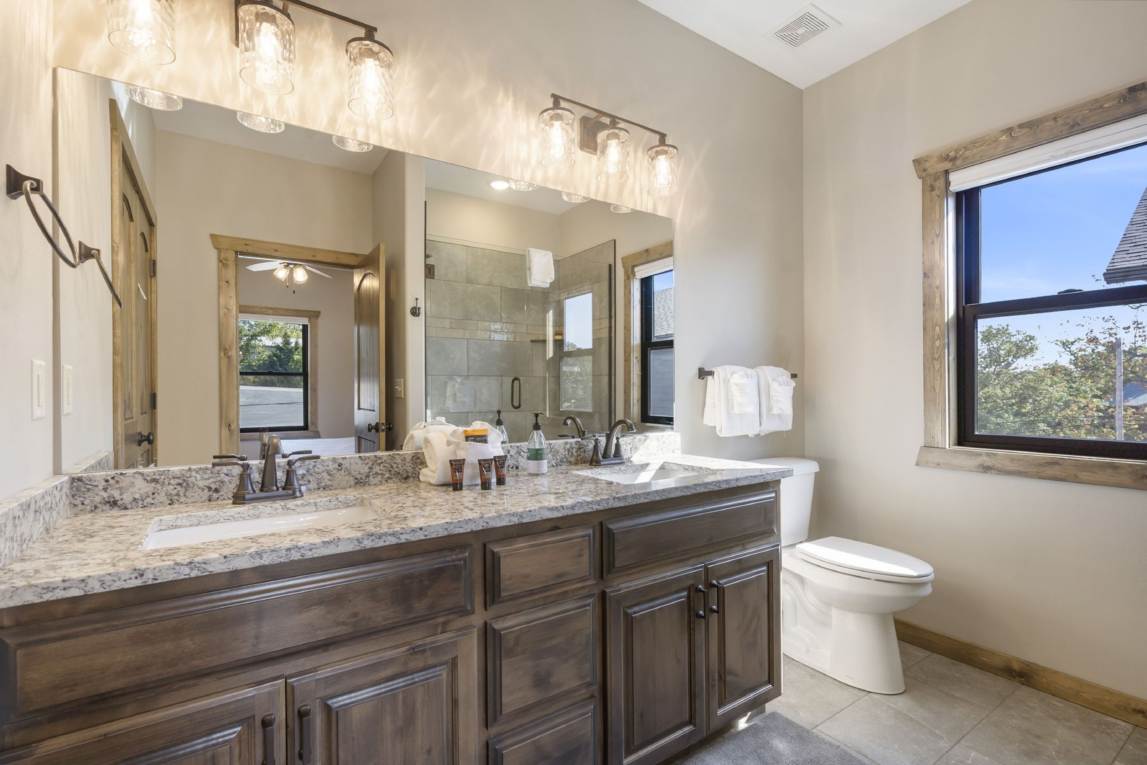 A modern bathroom with a large vanity, a double sink, a toilet, and a large mirror.