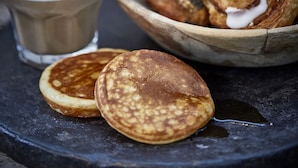 A breakfast setting with pancakes, a glass of milk, and a bowl of pastries.