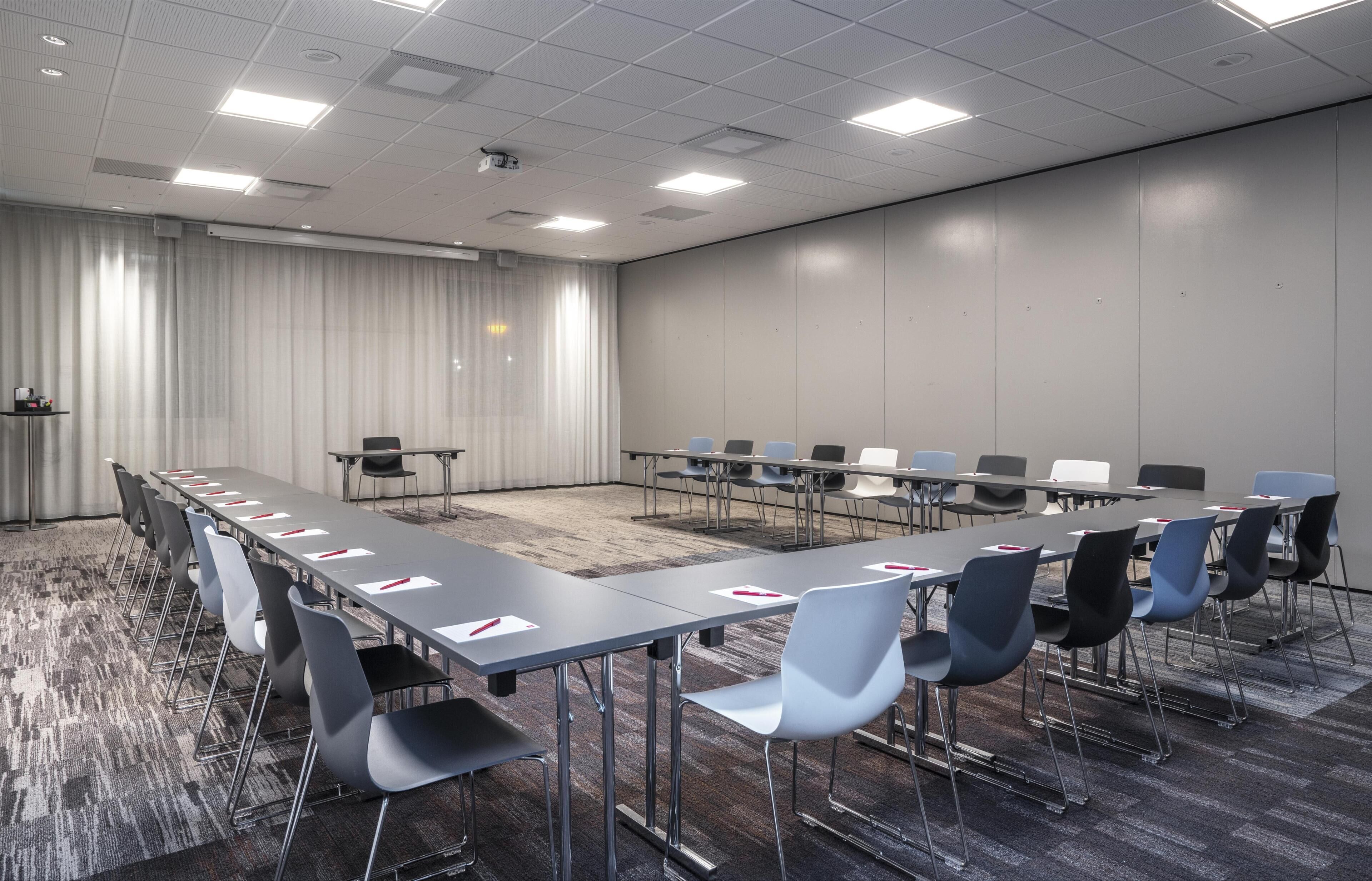 A conference room with a long table, chairs, and a carpeted floor.