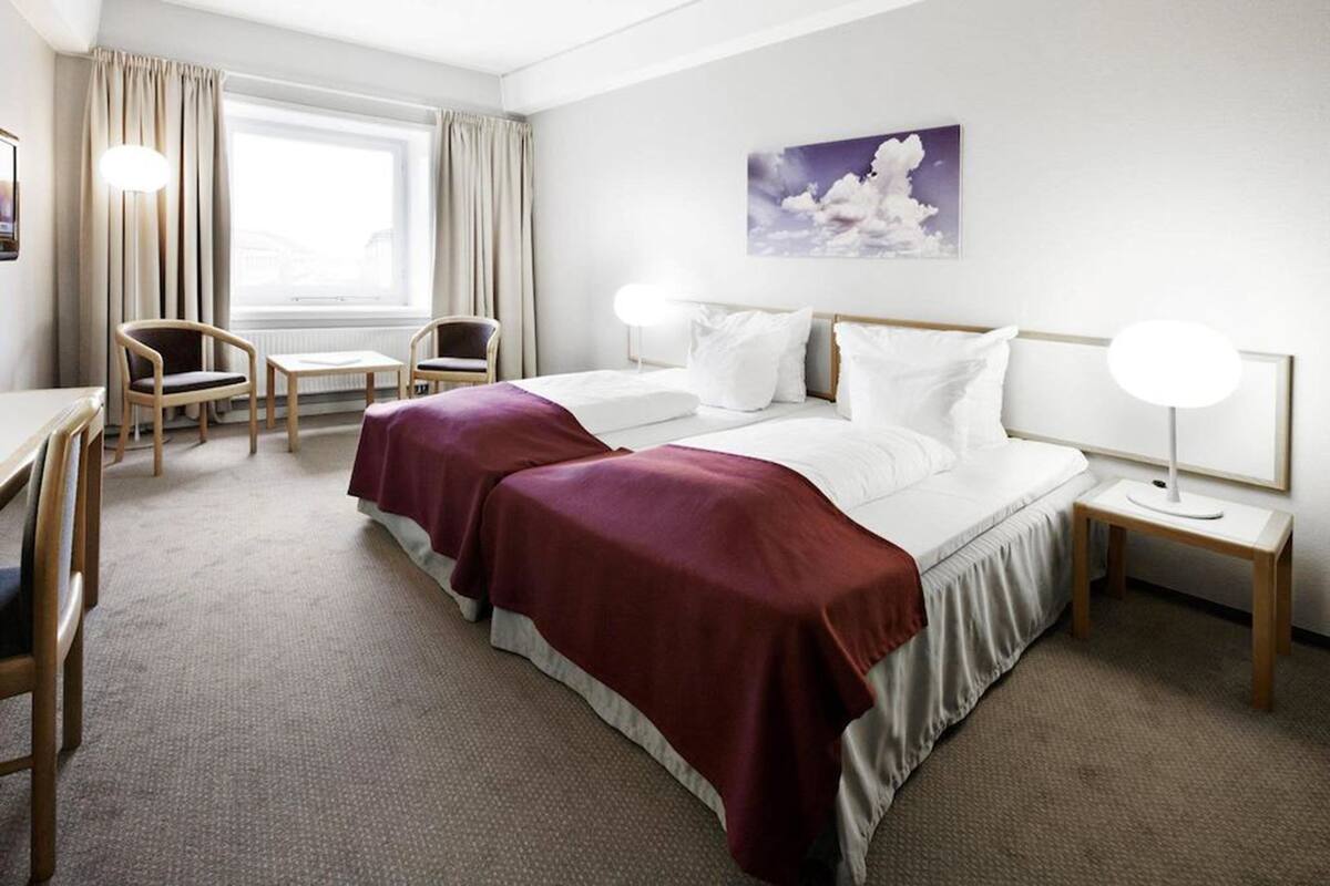 Et hotelværelse med en stor seng, to sengeborde, et skrivebord og en stol.