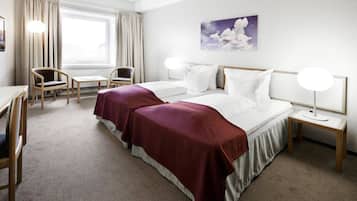 A hotel room with a large bed, two bedside tables, a desk, and a chair.