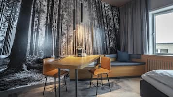 A room with a large window, a bed, a seating area with a sofa and a table with chairs.