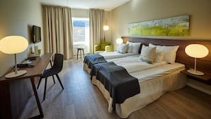 A hotel room with two beds, a desk, a chair, a TV, and a painting on the wall.