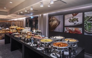 A buffet area with various food options, a restroom, and a seating area with tables and chairs.