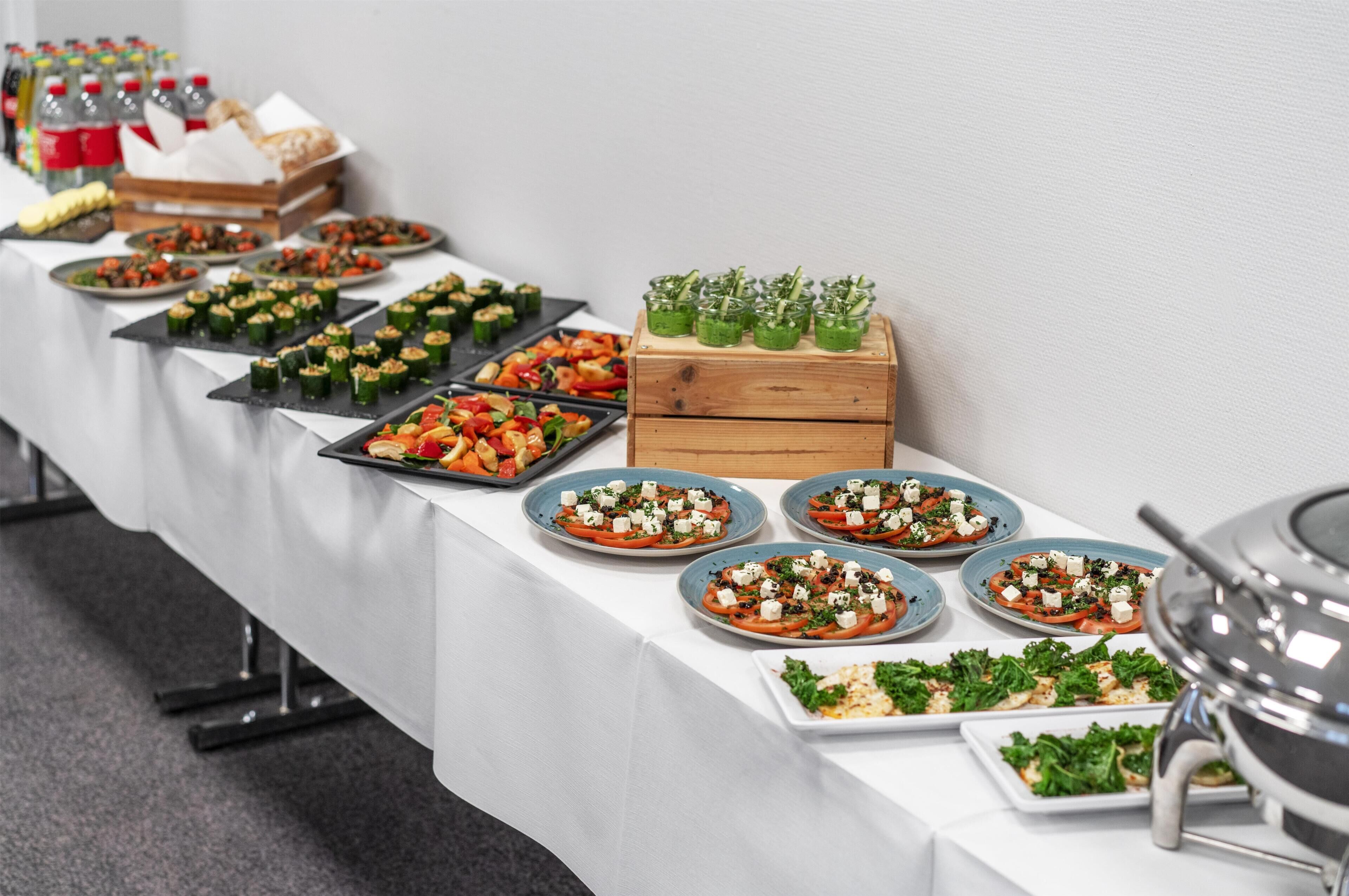 A buffet table with various food options including salads, appetizers, and a selection of beverages.
