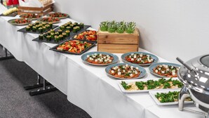 Una mesa de buffet con diversas opciones de comida, incluyendo ensaladas, aperitivos y una selección de bebidas.