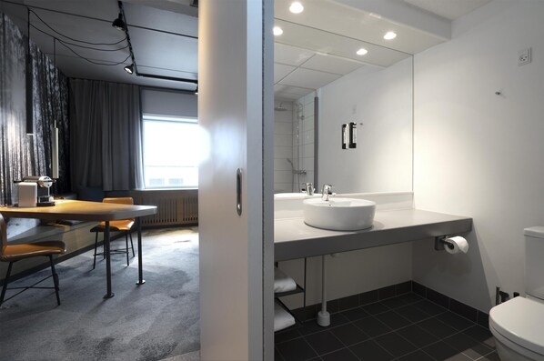 A modern bathroom with a white sink, a toilet, and a shower area.