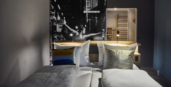 Un dormitorio moderno con cama, mesitas de noche y un gran mural en la pared.