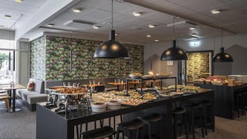 Un'area buffet con diversi cibi, sgabelli da bar e lampade a sospensione.