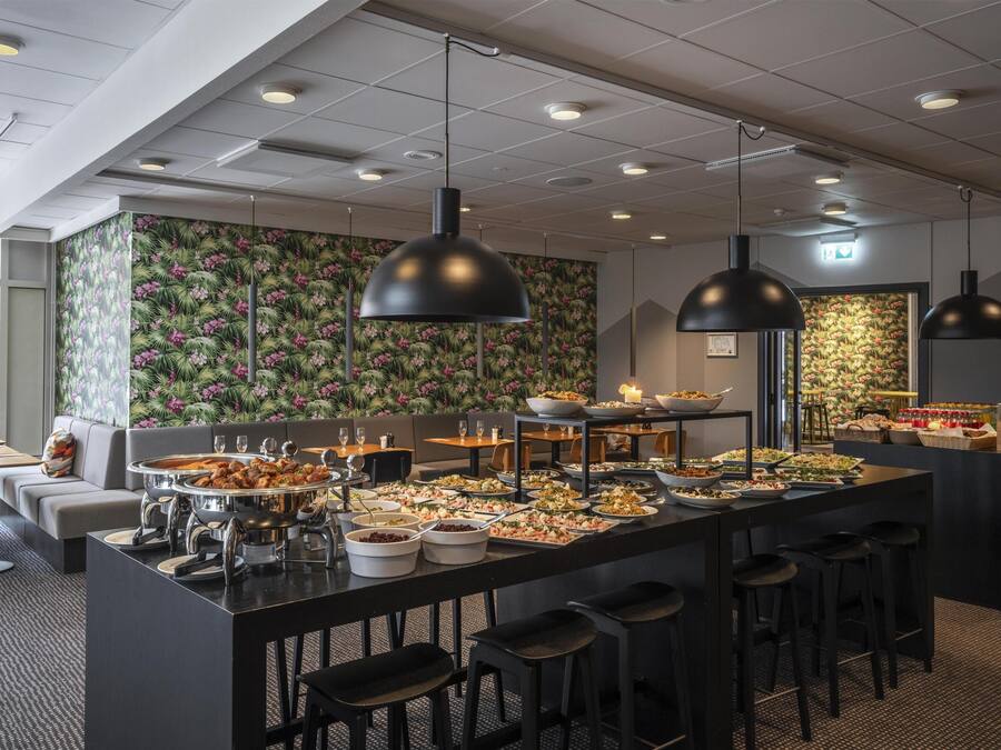 Un'area buffet con diversi cibi, sgabelli da bar e lampade a sospensione.