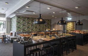 Een buffetopstelling met diverse gerechten, barstoelen en hanglampen.