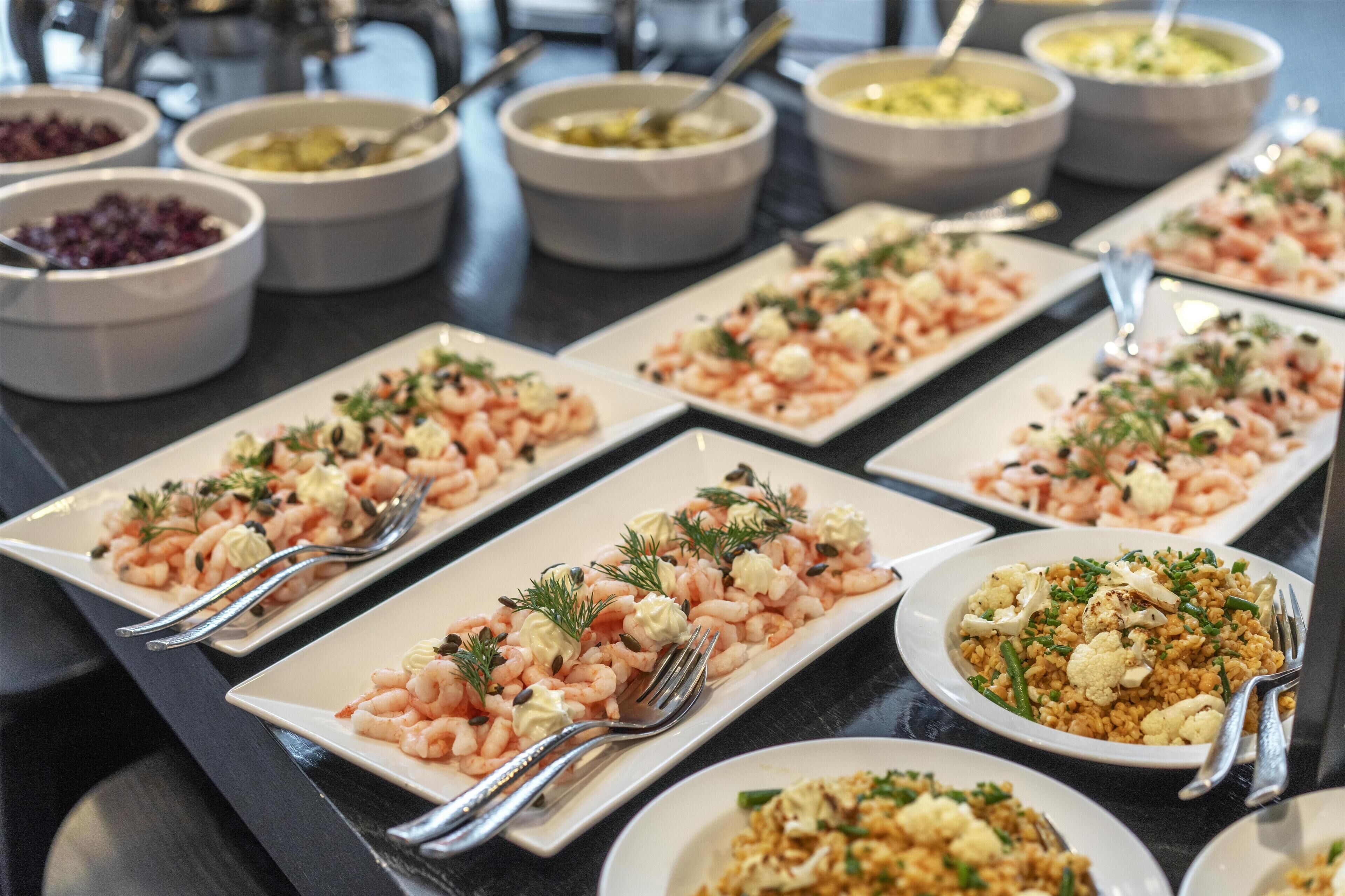 A buffet table with various dishes including shrimp, rice, and vegetables.