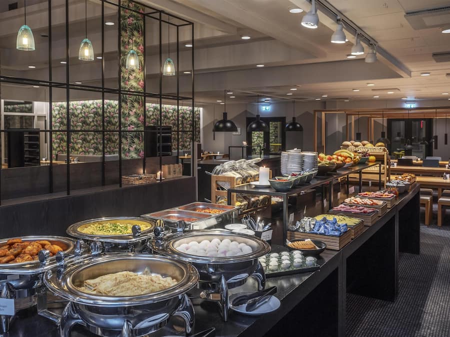 Zona de bufé con diversas opciones de comida y un área de estar al fondo.