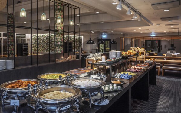 Zona de bufé con diversas opciones de comida y un área de estar al fondo.