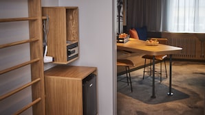 A modern room with a wooden desk, a built-in heater, and a dining area with a table and chairs.