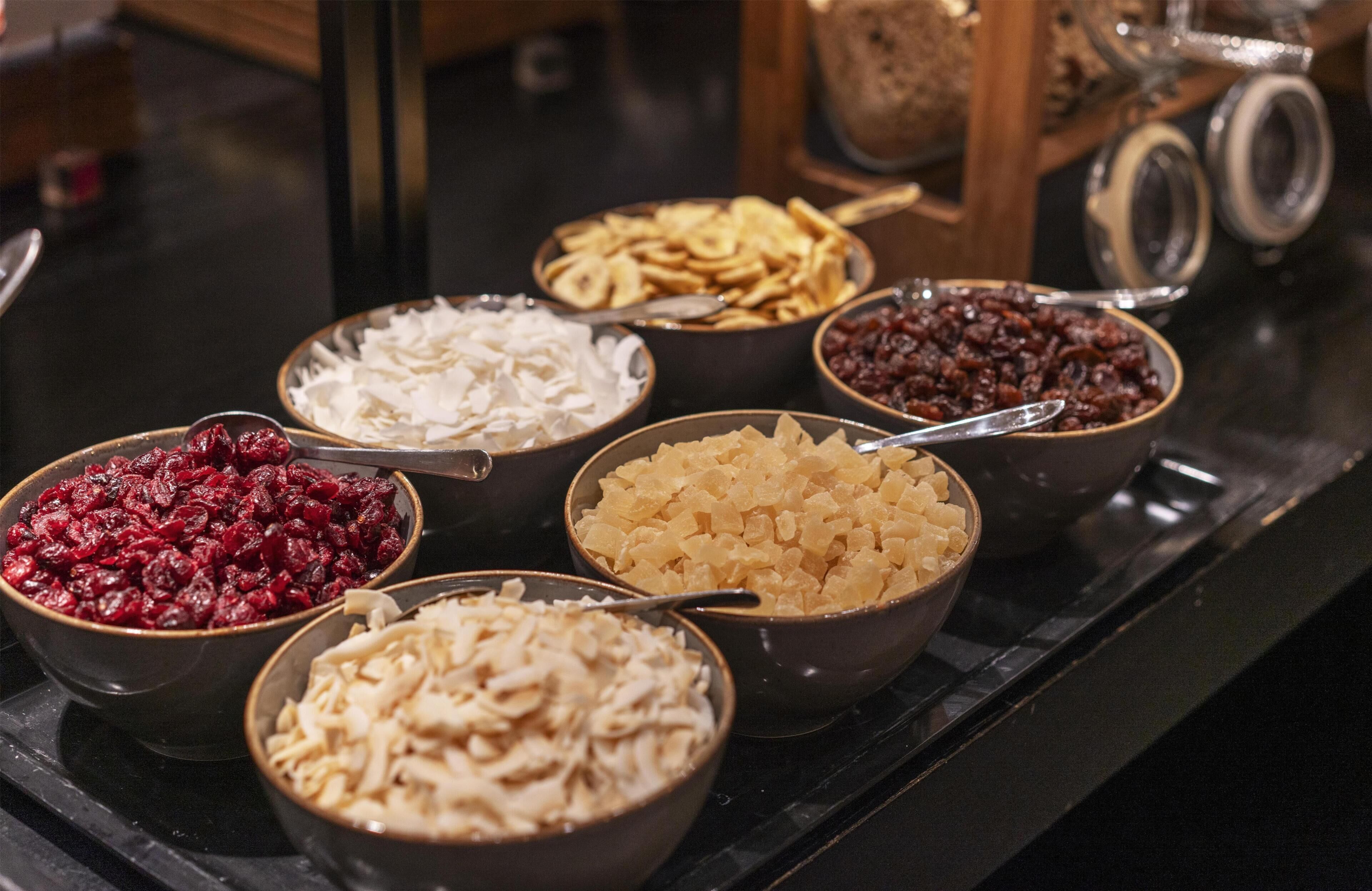 A selection of bowls containing various dried fruits and nuts on a countertop.