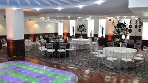 A banquet hall with round tables, white chairs, and floral centerpieces. - Hotel Arroyo de la Plata (Zacatecas)